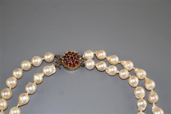 A double strand cultured baroque pearl necklace with yellow metal and garnet ? cluster clasp and one other simulated pearl necklace.